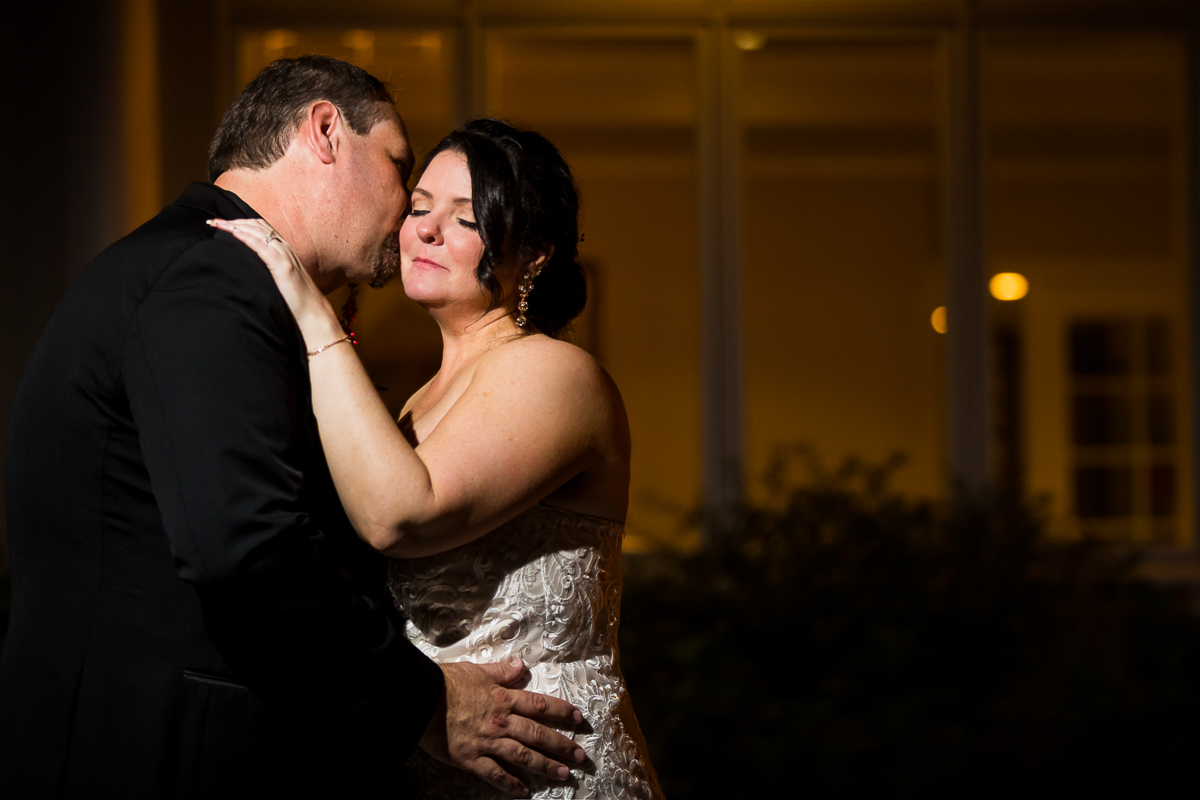 end of night photos groom kisses bride on cheek outside gettysburg hotel creative artistic wedding photographer