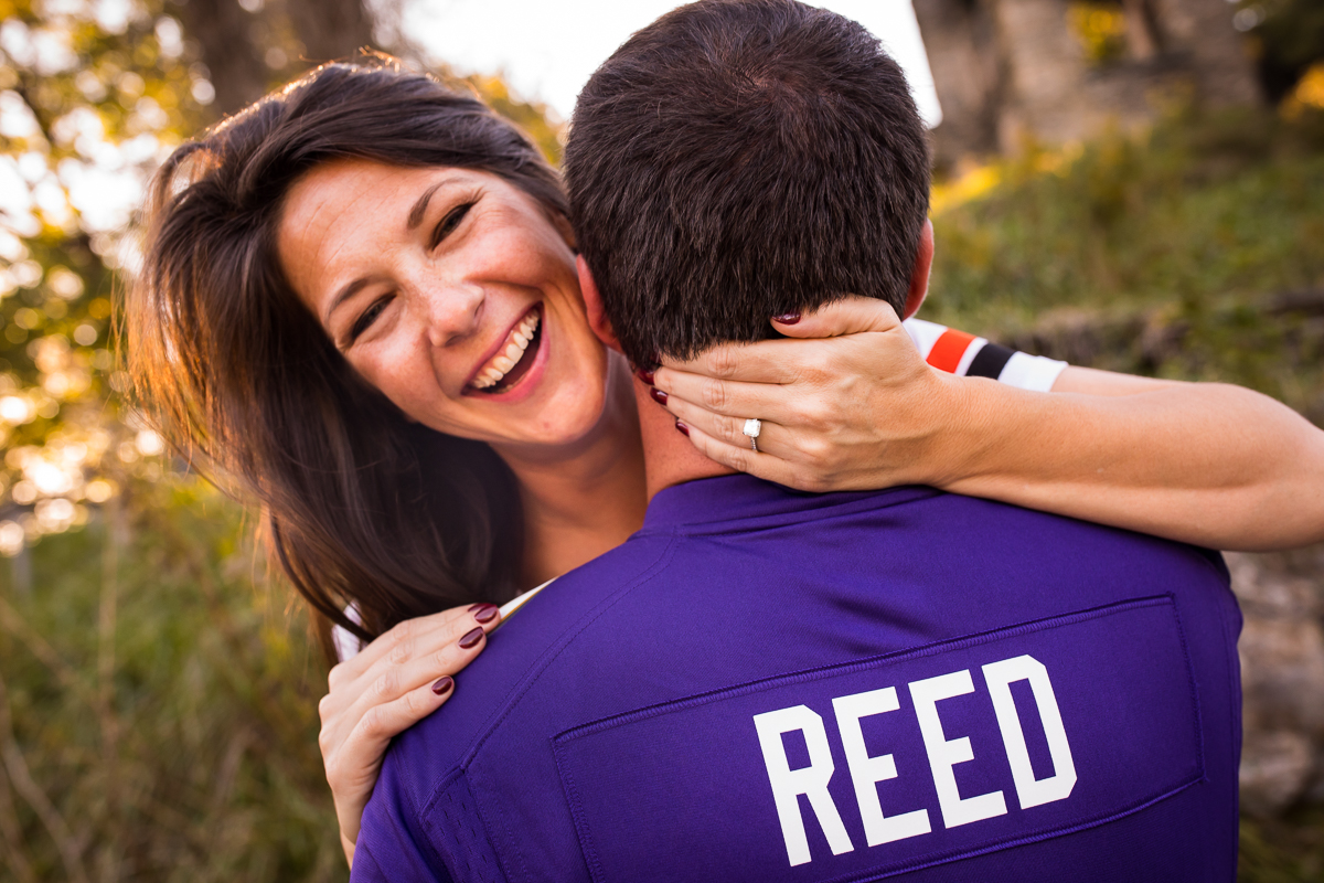 couple wearing college sport jersey laughing smiling with hand around neck 