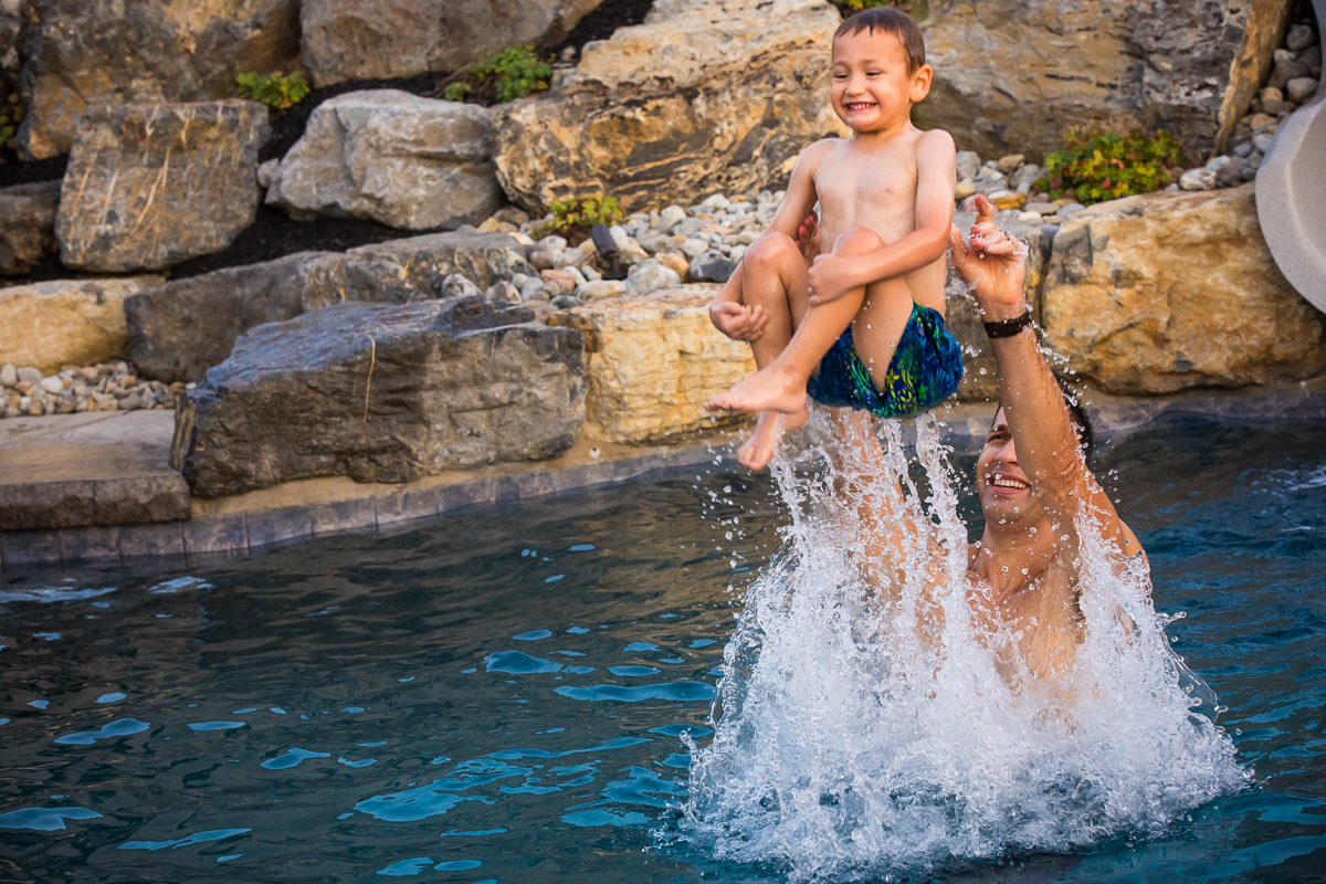 lifestyle family photographer central pa dad throwing sons in swimming pool
