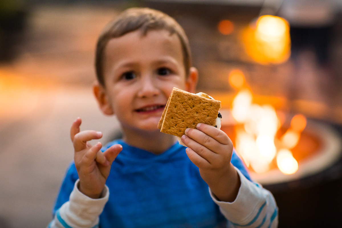 boy holding smore smiling in front of fire pit at family photo Lehigh valley photographer