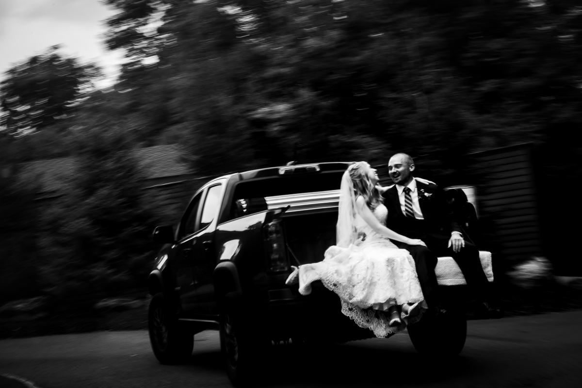 stroudsmoor terraview wedding photographer black and white photo of bride and groom riding in back of pickup truck smiling looking at each other