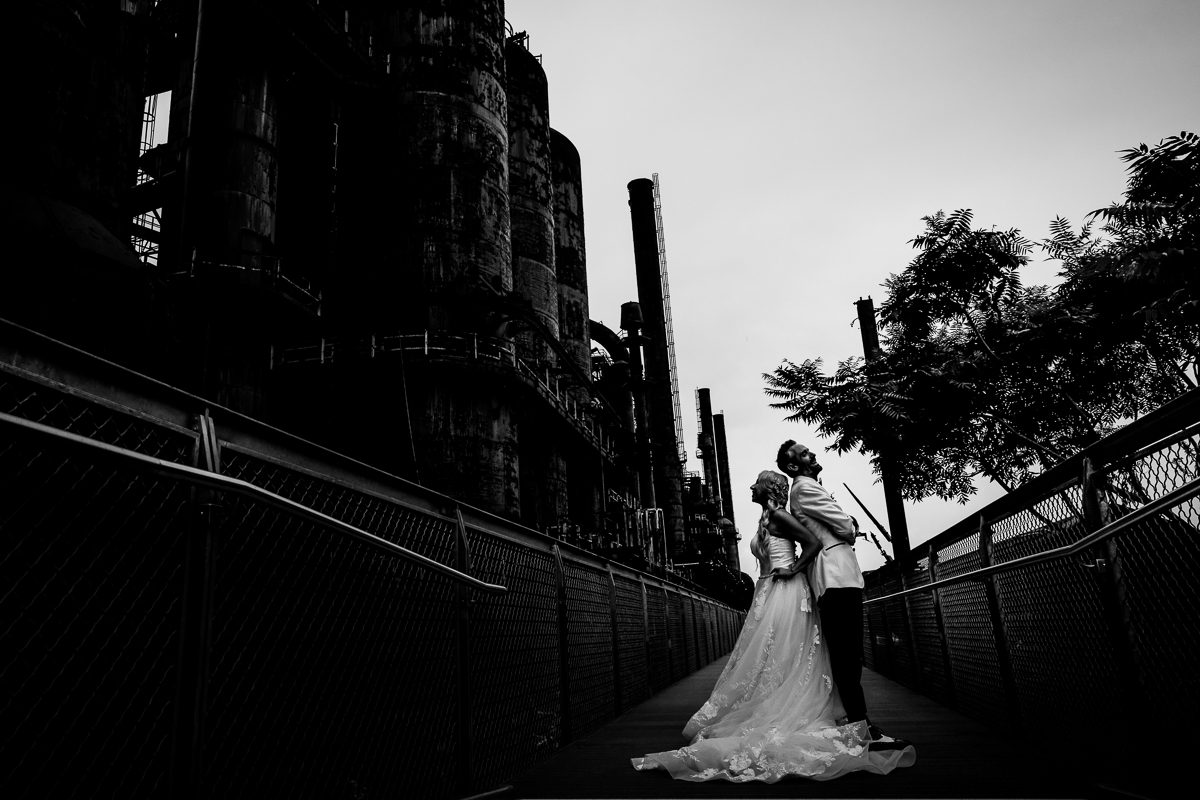 SteelStacks wedding after-session black and white photo of bride and groom standing back to back smiling and laughing creative architecture dramatic lines and lighting 