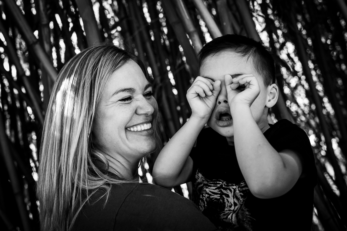 black and white photo of mom holding son laughing making funny faces at Maryland zoo family photographer