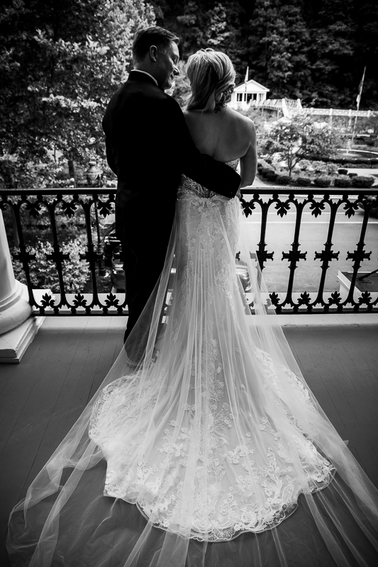 black and white photo of bride and groom holding each other bride's train shown at Omni Bedford Springs wedding
