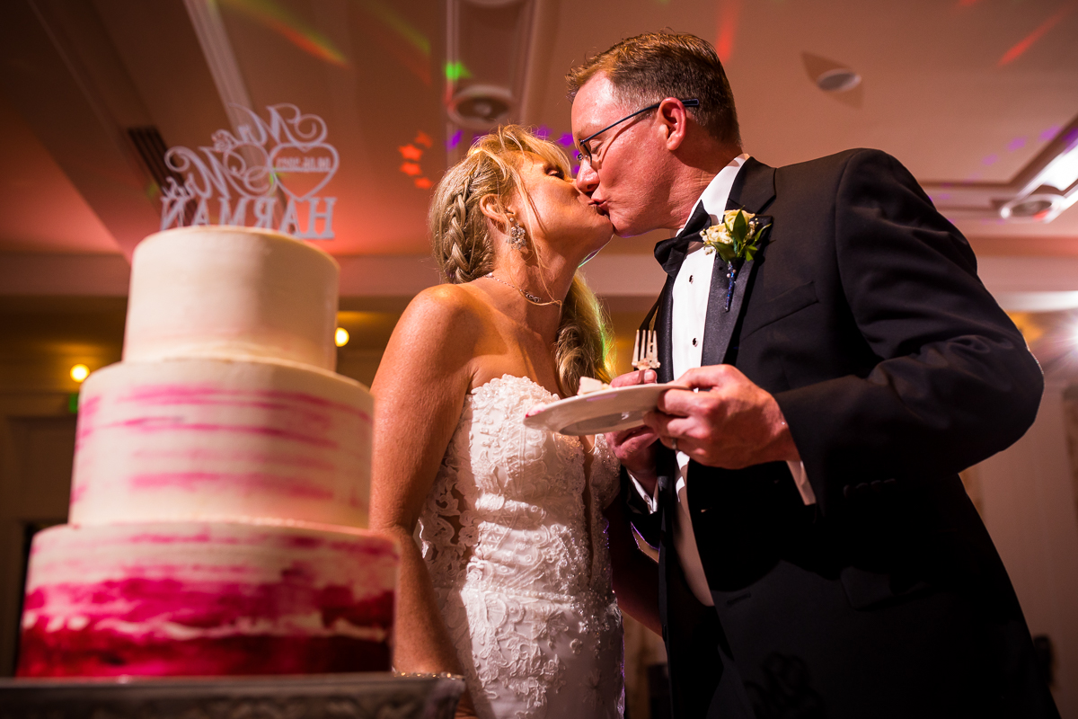 bride and groom share a kiss after slicing the first piece of cake at wedding reception omni Bedford springs