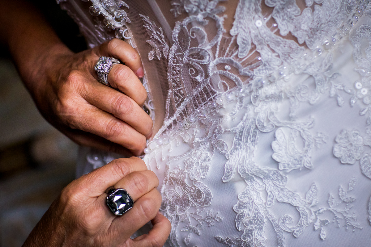 close up detail of bride's wedding dress buttons being fastened 