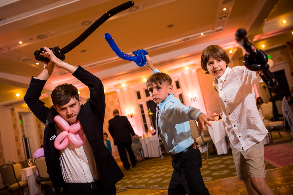boys holding balloon swords during wedding reception
