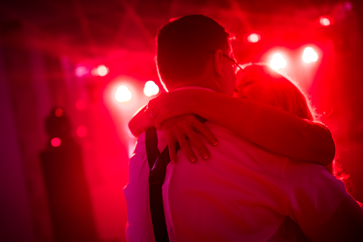 vivid vibrant colorful wedding photographer couple dances with red uplighting behind them 