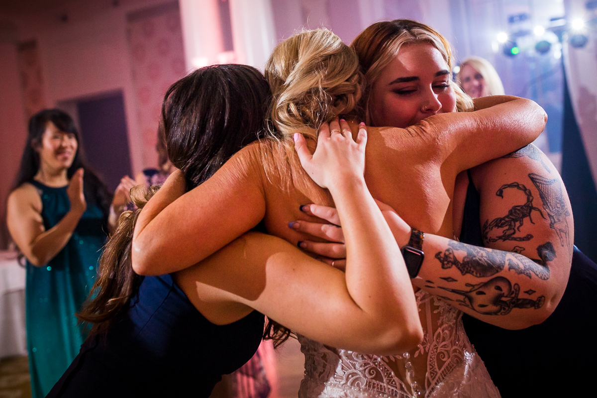 bride being hugged by groom's daughters at wedding reception in colonnade ballroom 
