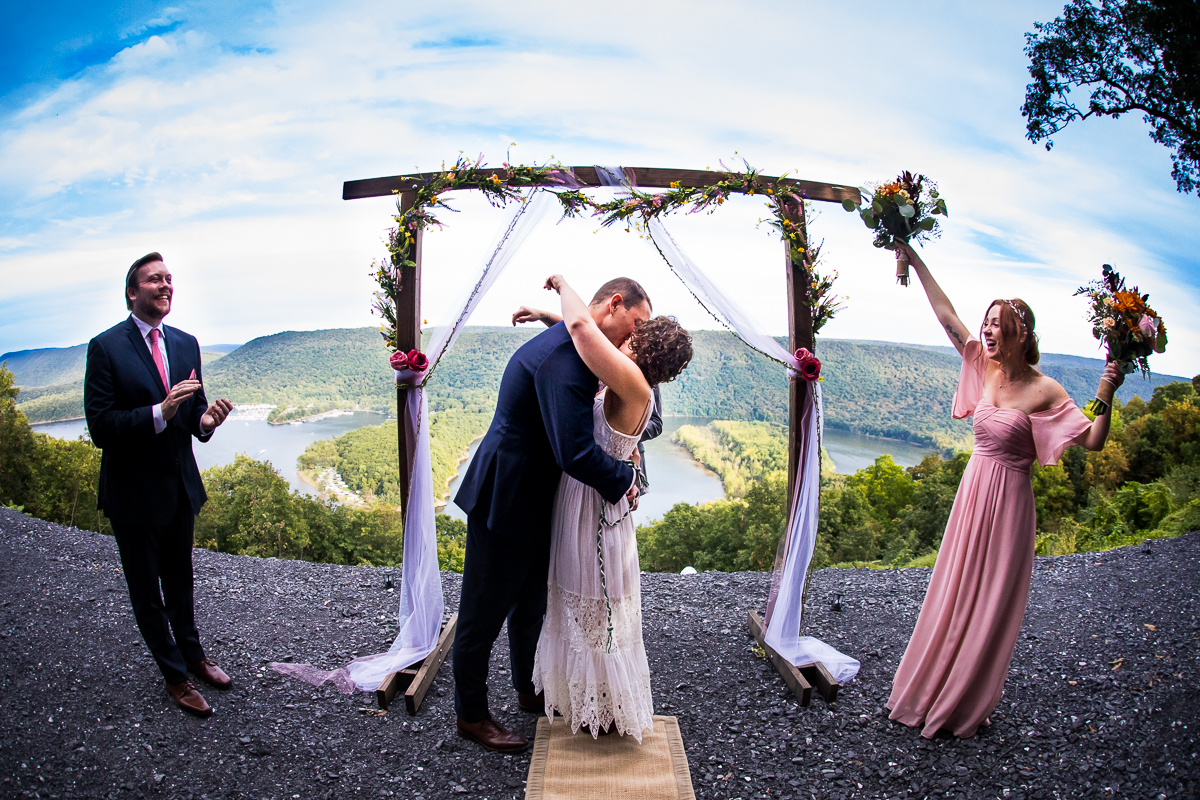 wedding party cheers as bride and groom share first kiss at Bella vista raystown lake wedding ceremony 