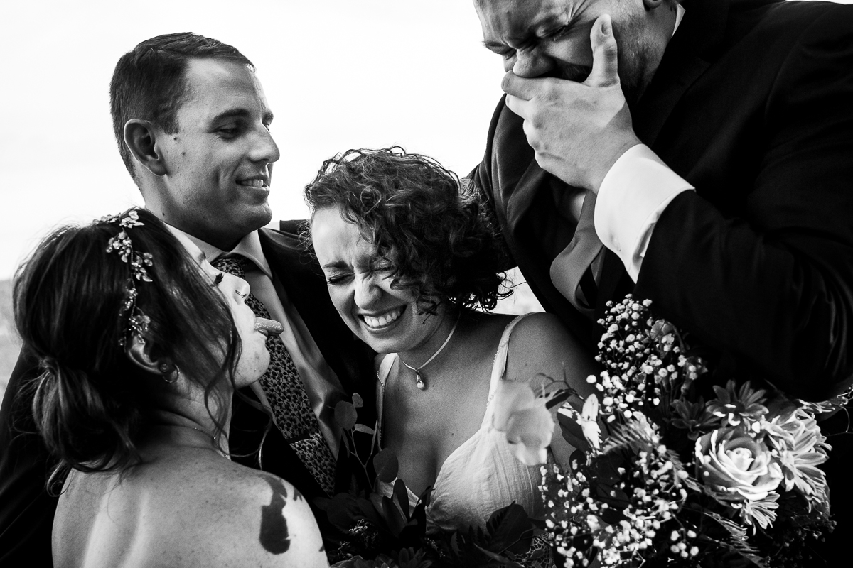 black and white photo of bride and groom surrounded by wedding party making faces authentic candid wedding photographer