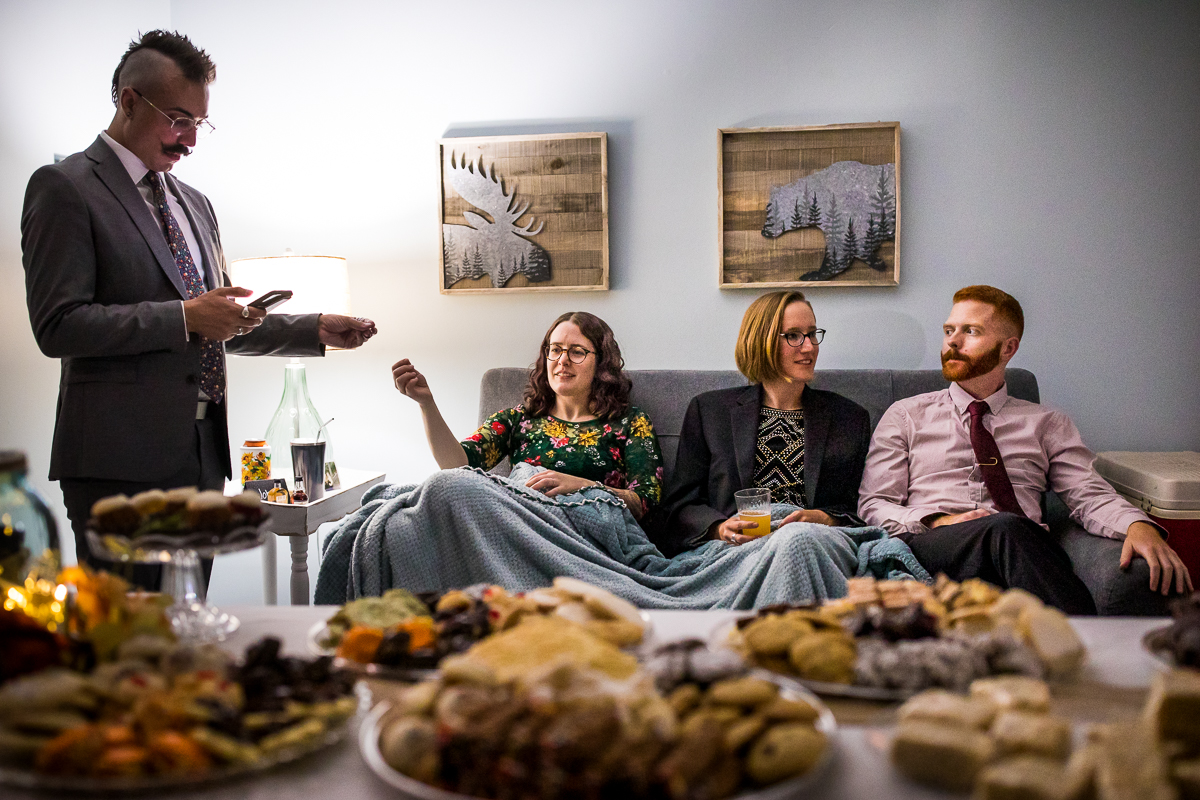 wedding guests sitting on couch in front of food displays during wedding after party