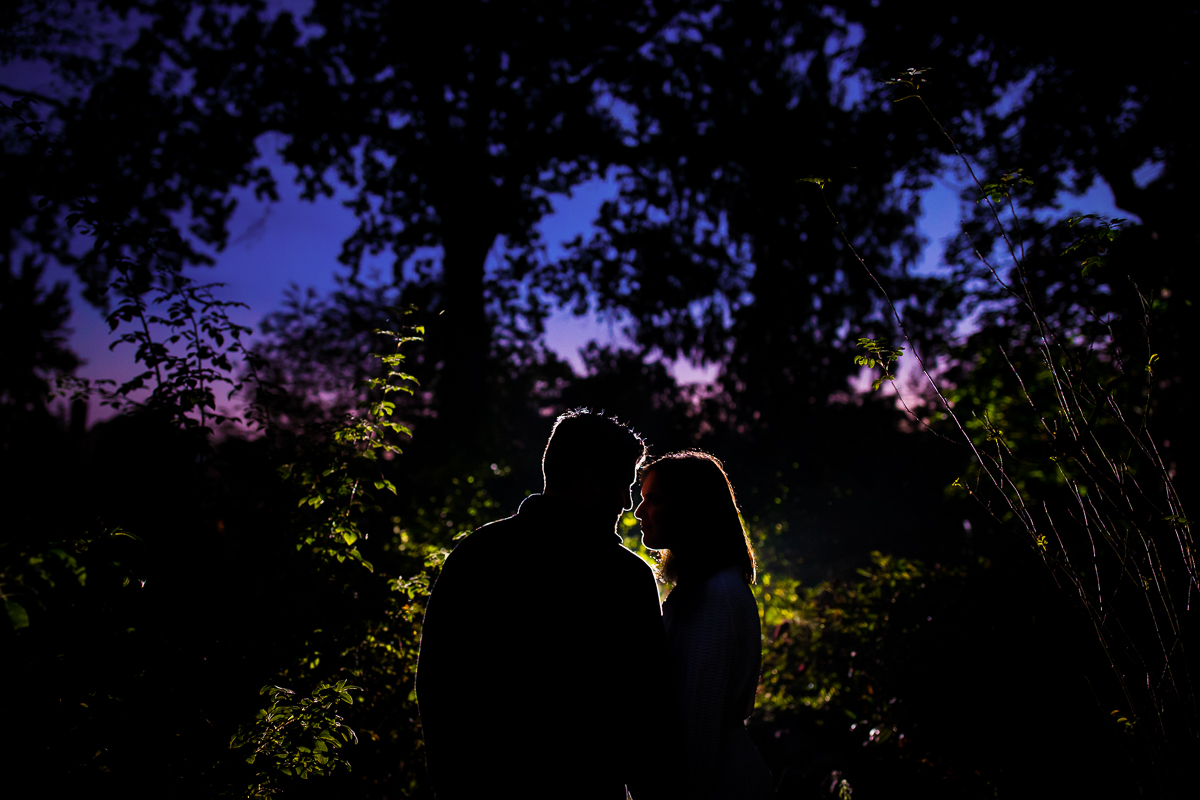 creative artistic nj engagement photographer couple silhouetted against twilight sky in MacCulloch garden morristown
