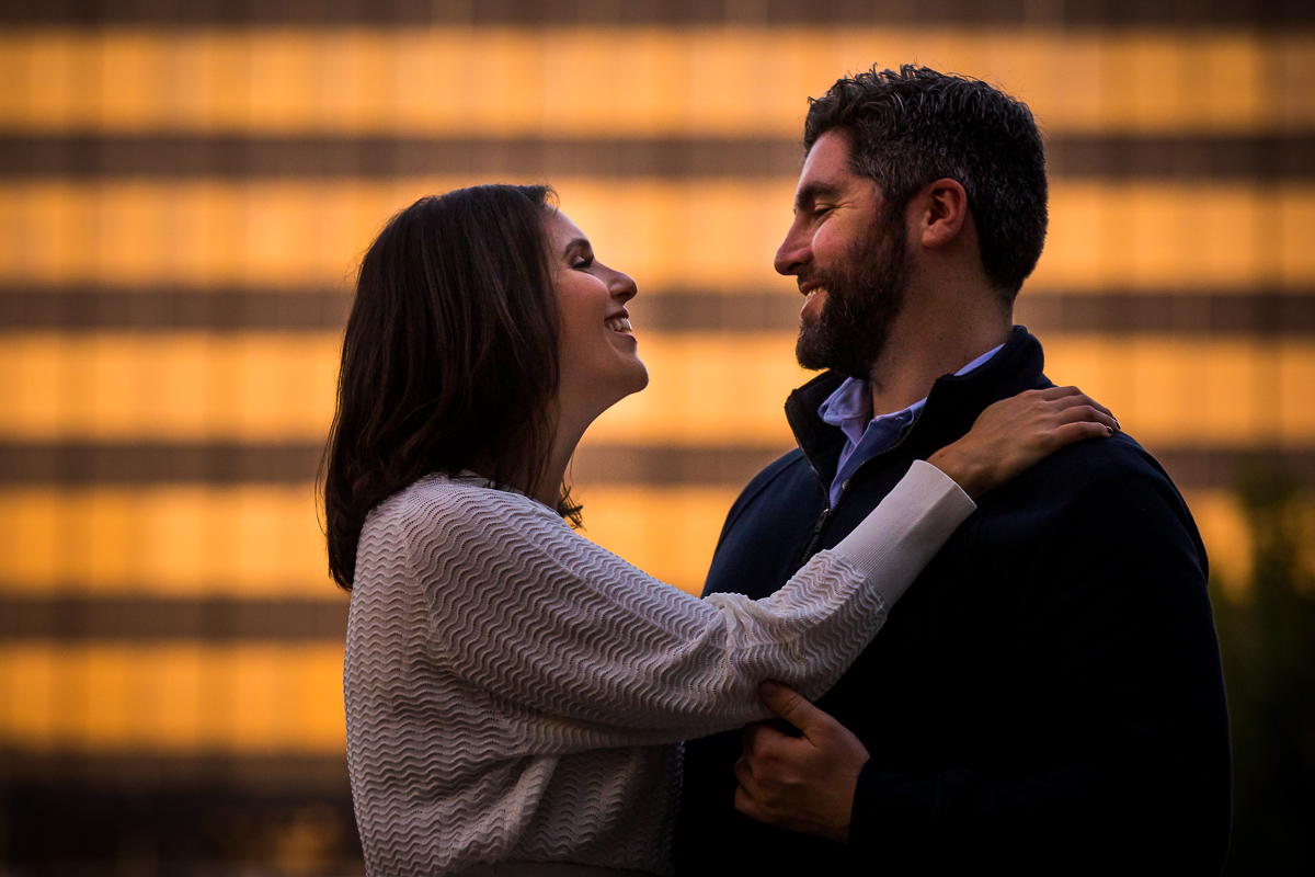 couple looking at each other and smiling gold lights reflected in background