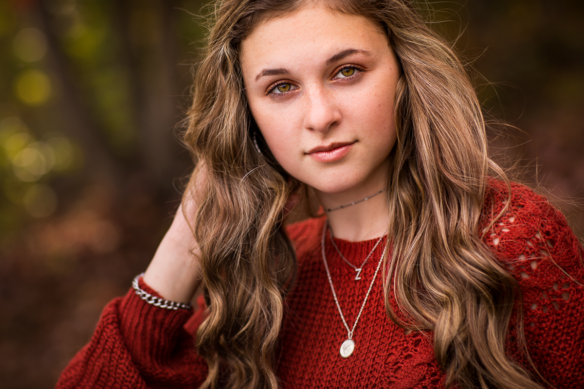 girl looking at camera touching hair outdoors during senior portrait session