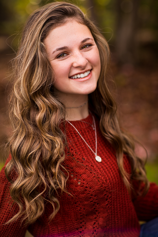 best central PA senior portrait photographer girl wearing red sweater smiling at camera