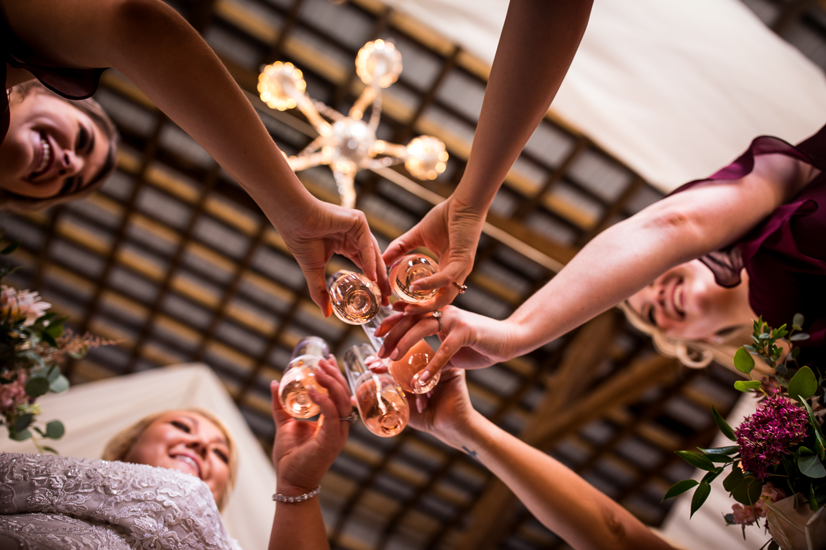 creative angle of bride and bridesmaids toasting after getting ready