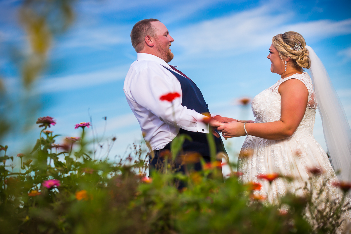 creative artistic central pa wedding photographer bride and groom holding hands laughing with each other in field of wildflowers