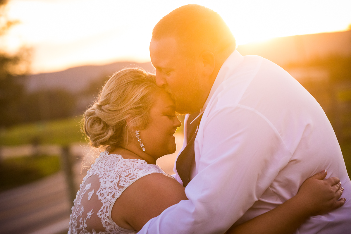 bride and groom portraits during golden hour groom kissing bride on forehead best central pa wedding photographer