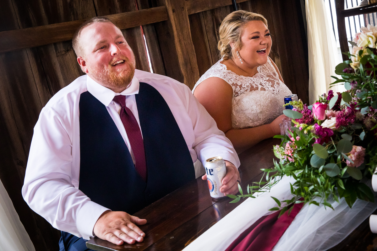 bride and groom smiling and laughing during guest speeches