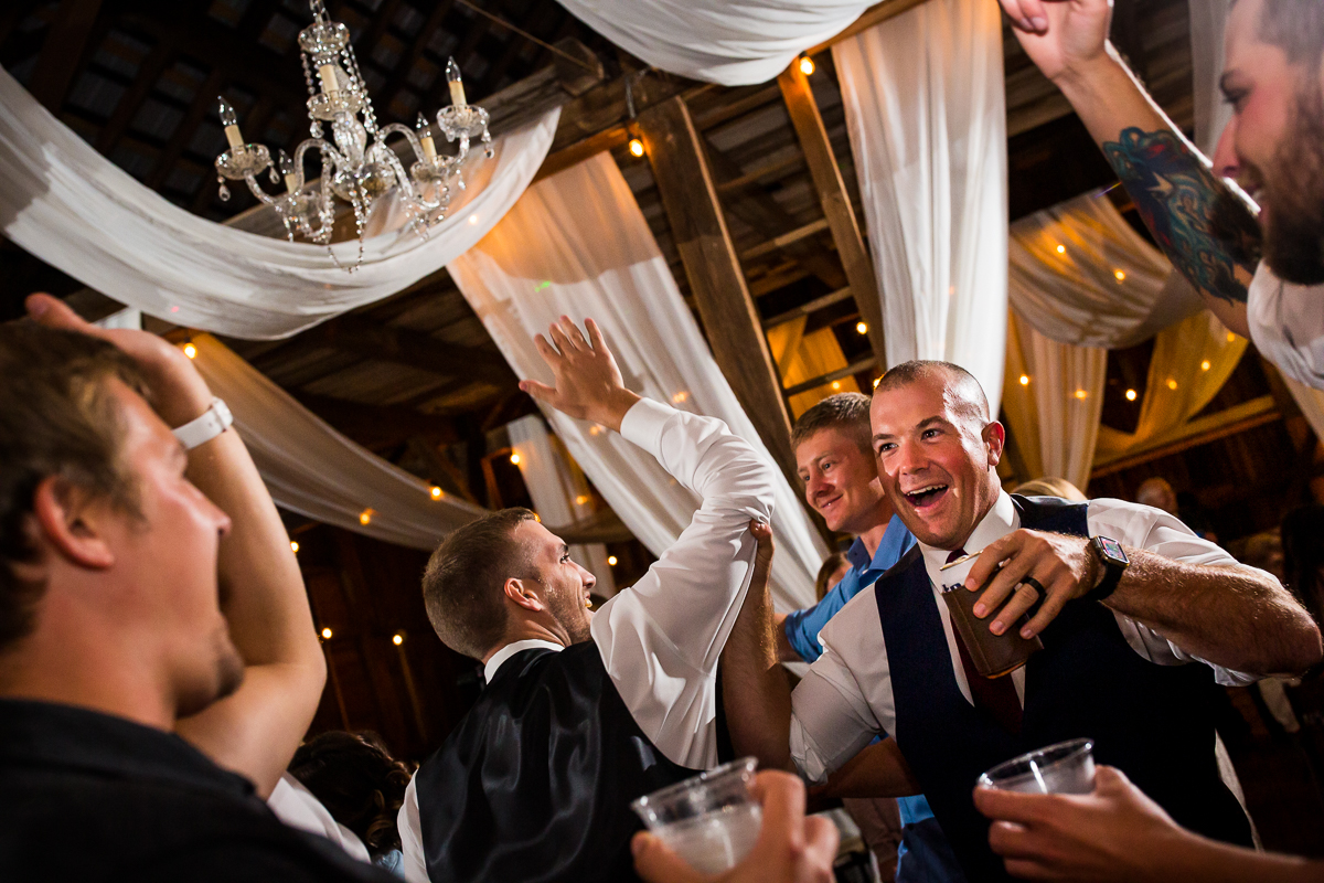 groomsmen high fiving holding drinks at wedding reception