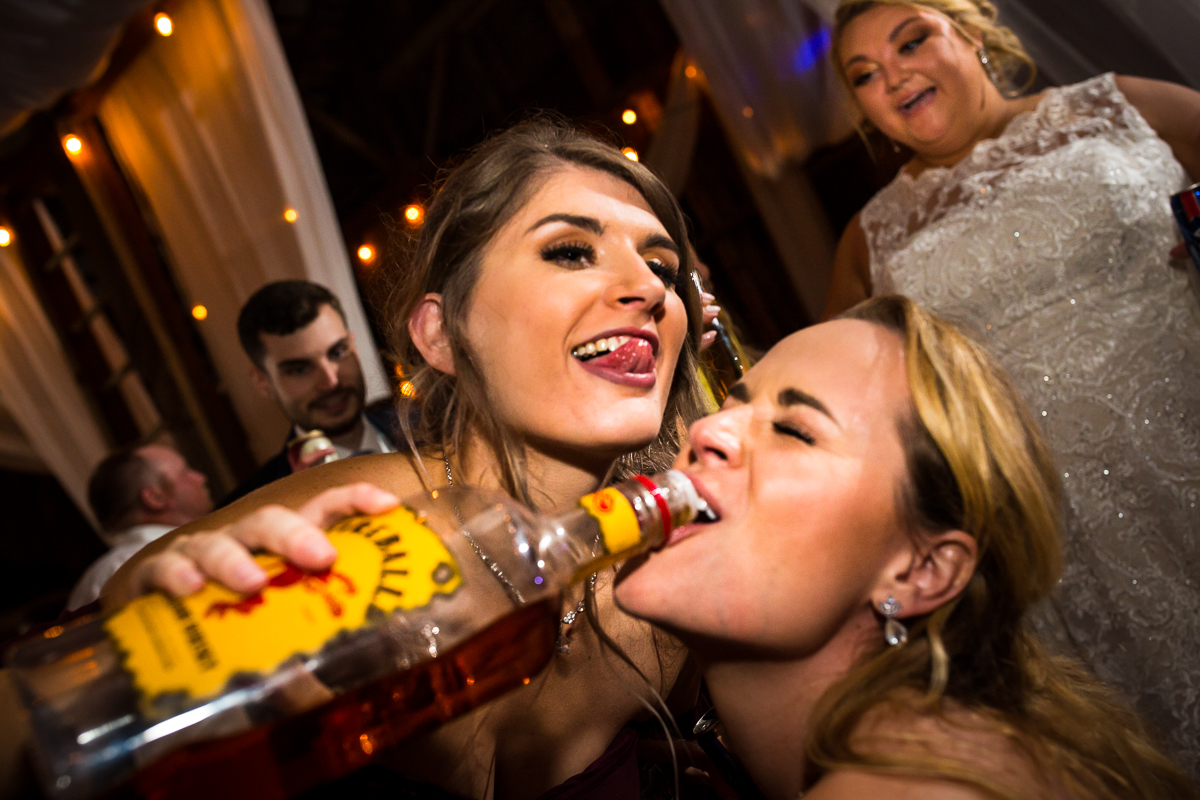 guests pouring shots with a bottle or fireball bride smiles in background heritage restored