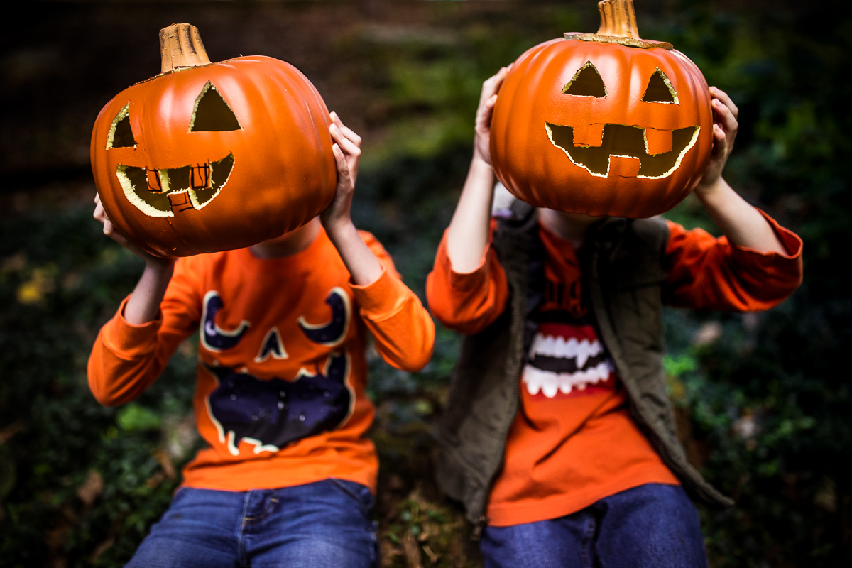 fun halloween inspired family lifestyle session two boys holding carved pumpkins in front of their heads