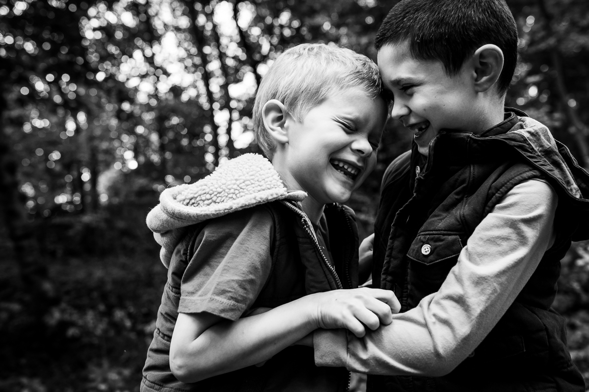 black and white photo of two boys laughing and smiling at each other candid authentic real life family photographer