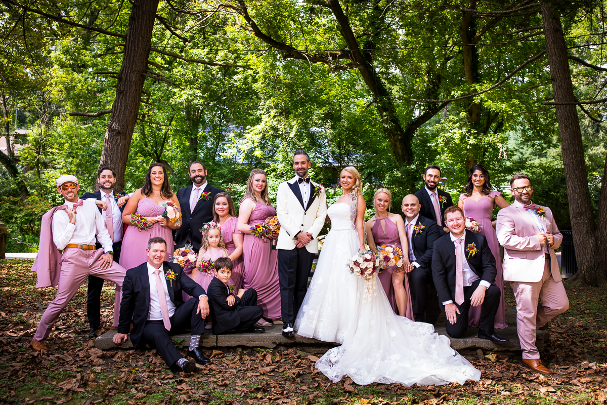 wedding party standing smiling vogue style at park with trees in background 