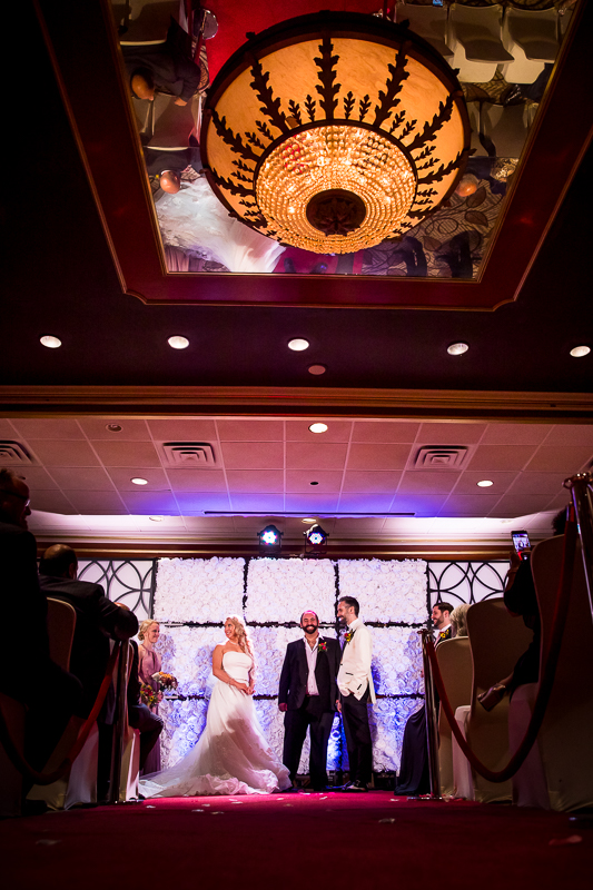 bride and groom standing at end of altar waiting for rings red carpet with unique lighting fixture