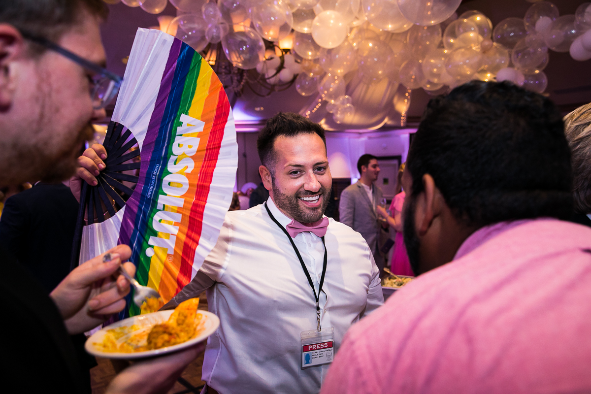 brides men waving rainbow absolut fan while guest enjoy cocktail hour food