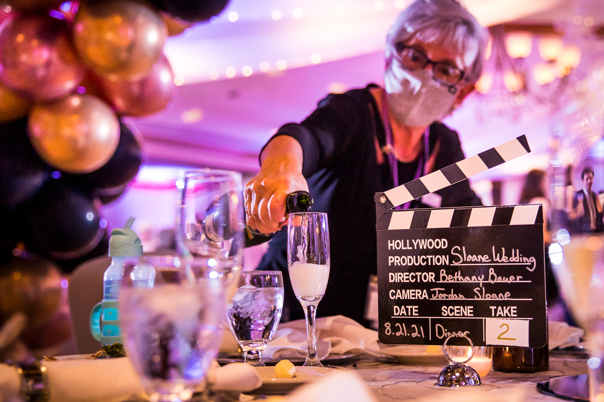 guest pouring champagne in glass with Hollywood scene sign as table decor unique reception decor