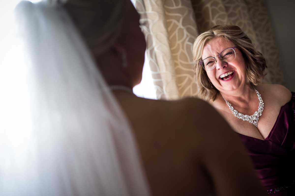emotional natural candid mom smiling when seeing daughter for first time on wedding day