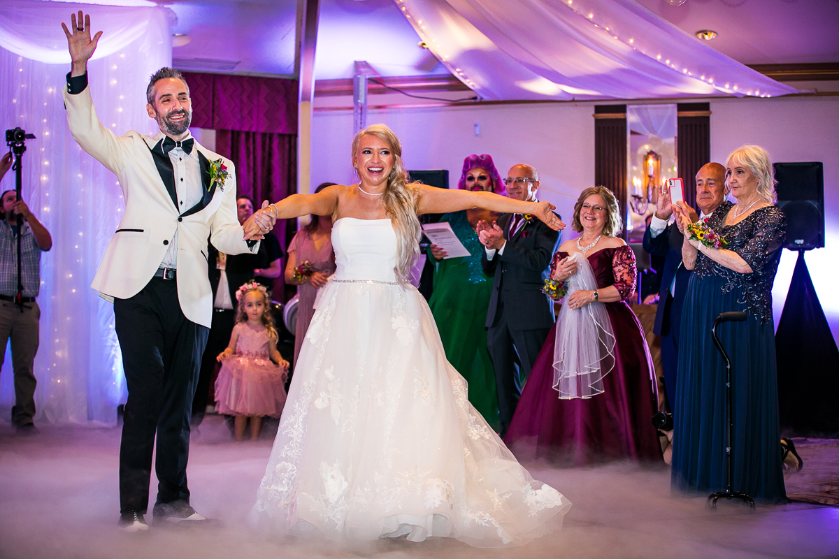 bride and groom smiling on dance floor guests clapping and smiling