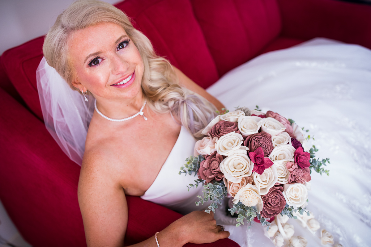 traditional bridal portrait bride holding bouquet sitting on red church smiling at camera