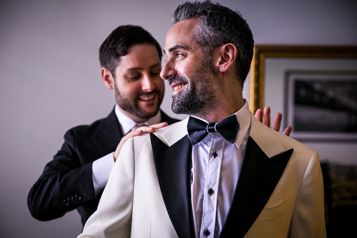groomsman helping groom straighten tux jacket during getting ready at Lehigh Valley conference center wedding