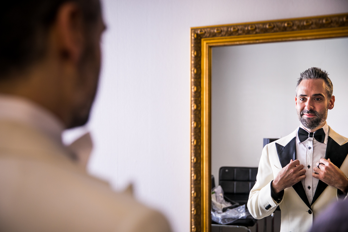 groom holding lapel looking at himself in the mirror getting ready central pa wedding photographer 