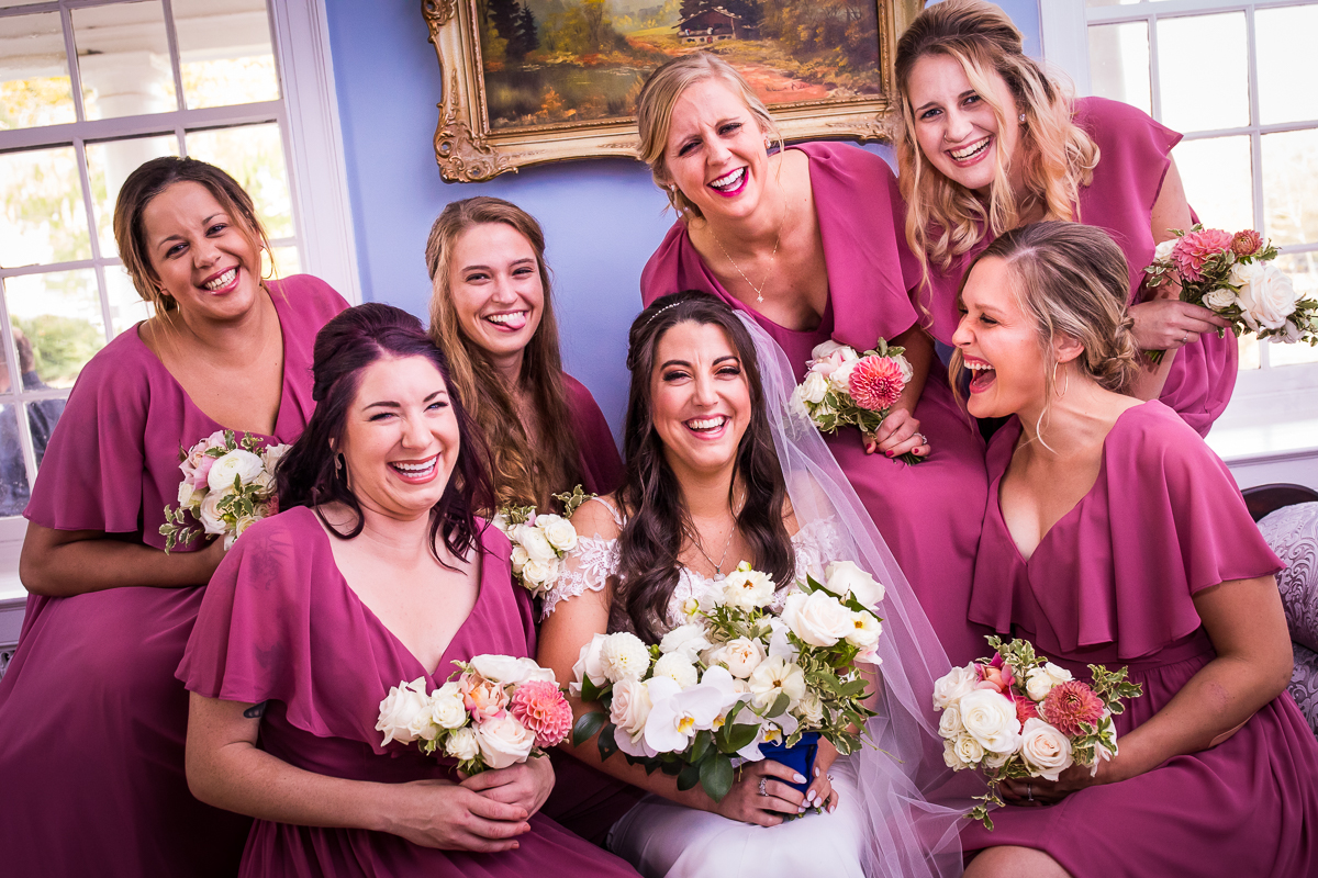 bride smiling and laughing with bridesmaids candid award winning wedding photographer central pa