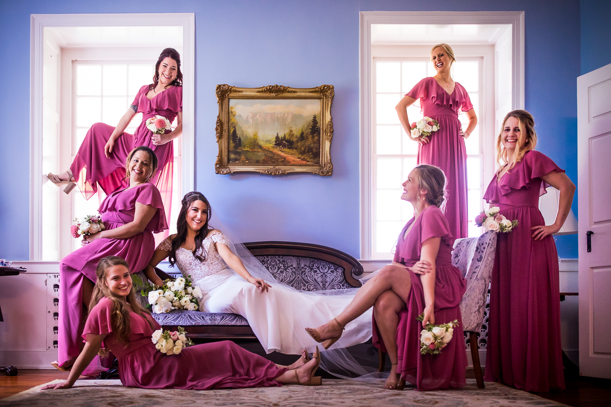 bride on setae and bridesmaids posing around her in allenberry resort mansion bridal suite