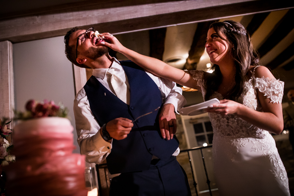 bride smashing cake in groom's face during cake cutting allenberry resort wedding reception