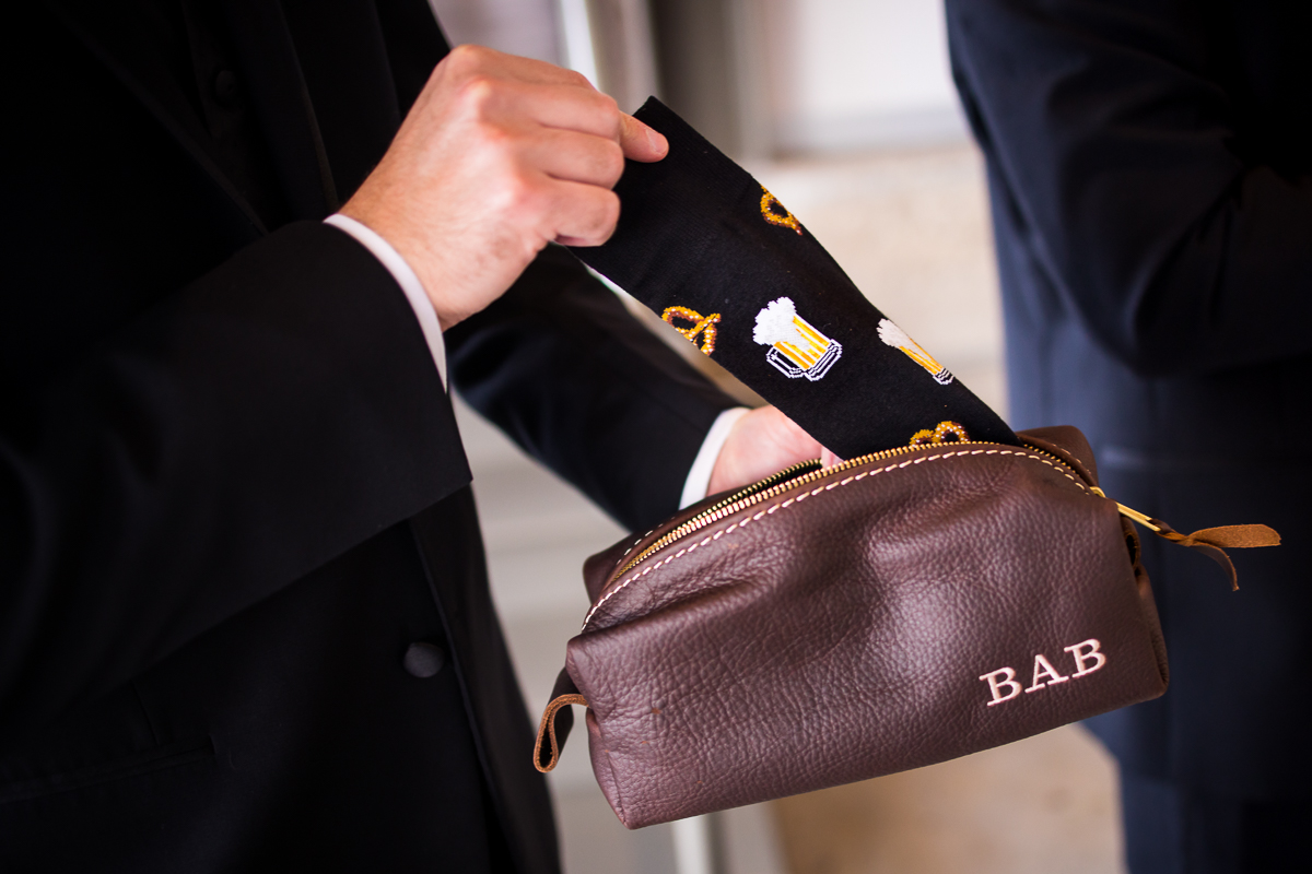 groomsman opening gift of monogrammed pouch and fun socks on wedding day