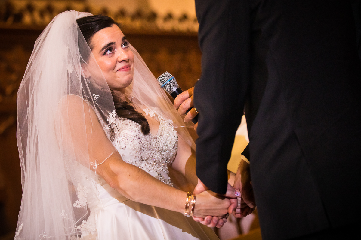bride smiling at grooms during vows in church 