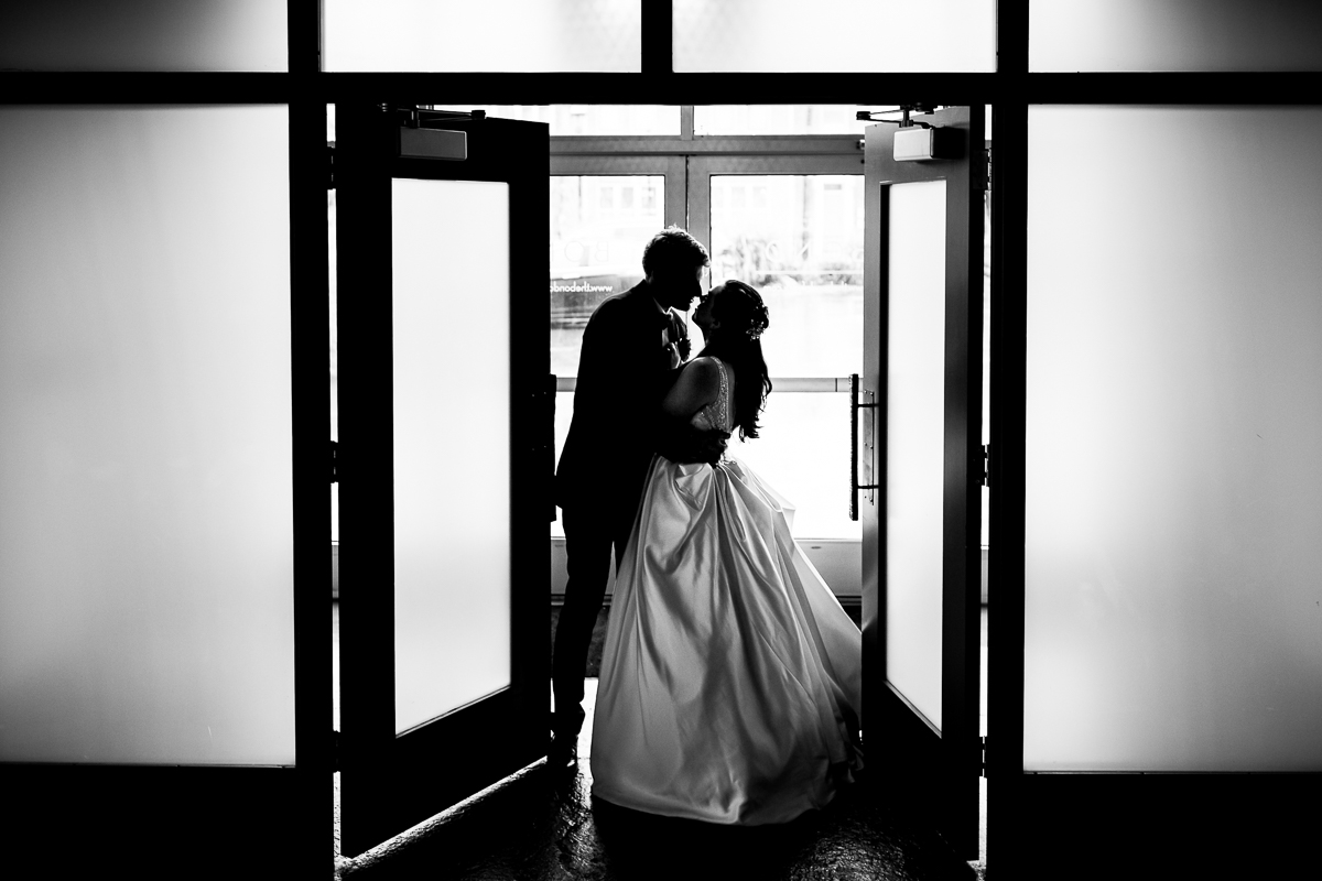 creative artistic wedding photographer black and white photo of bride and groom holding each other silhouetted against windows 