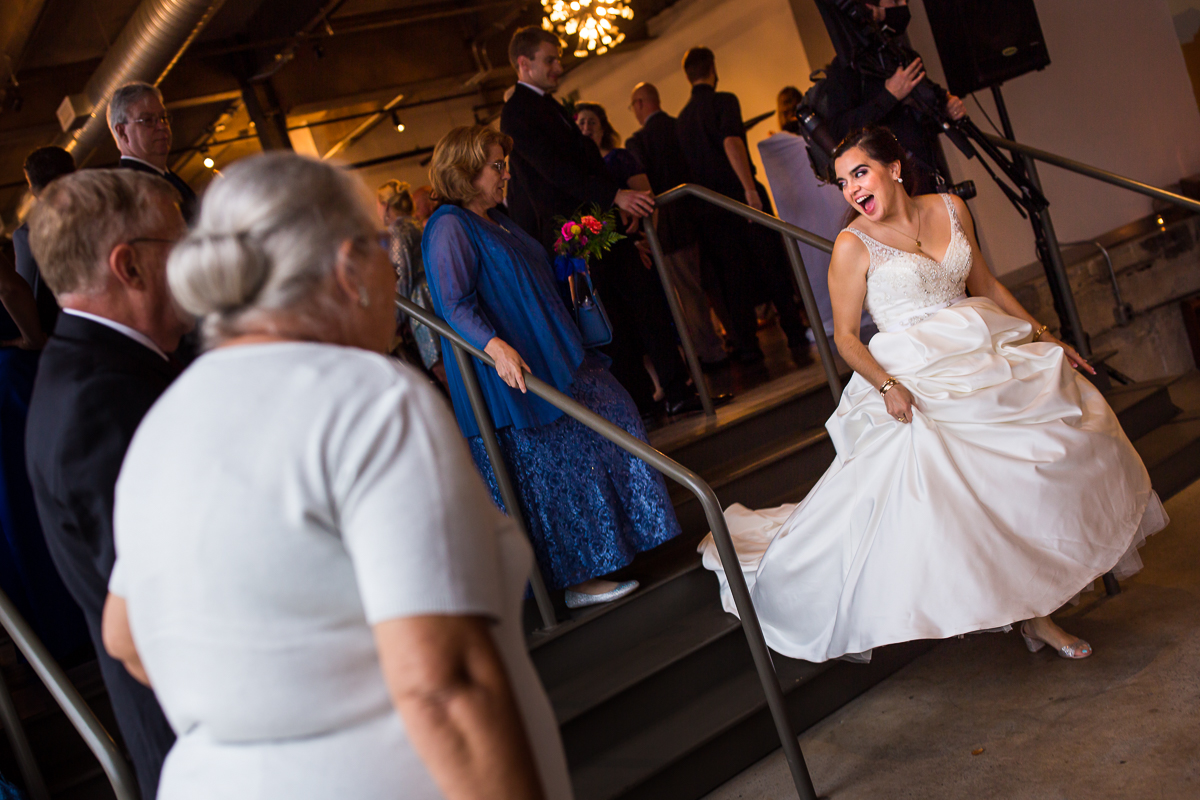 bride walking down stairs at the bond during cocktail hour holding ballgown with sparkly heels