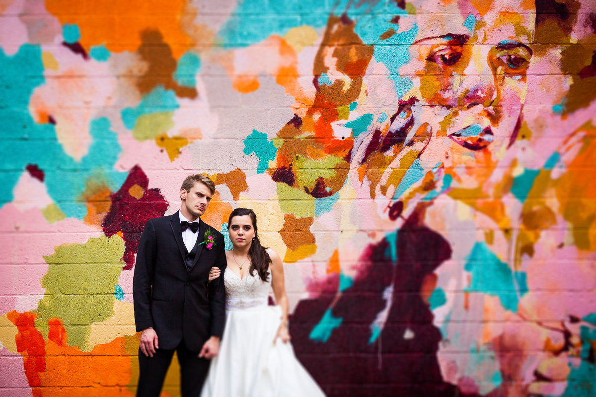 bride and groom with serious faces in front of mural downtown york pa