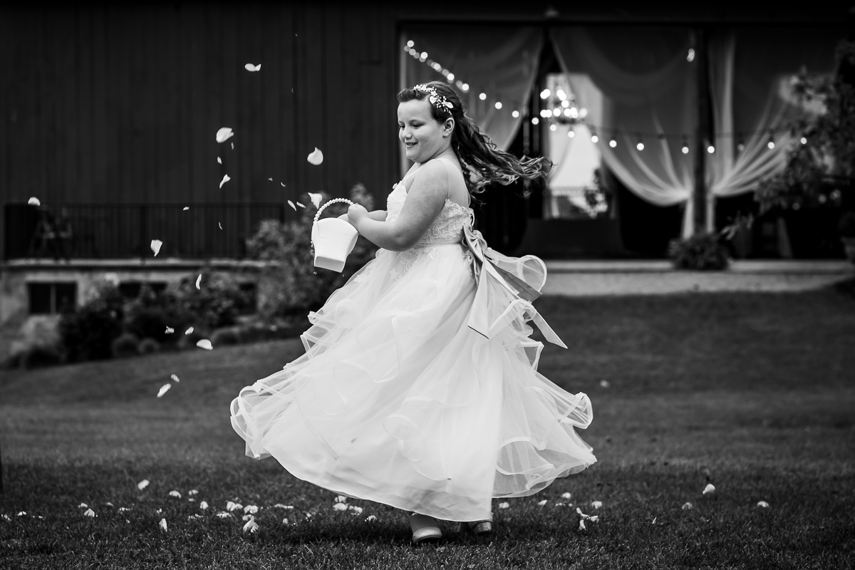 black and white photo of daughter twirling throwing flower petals outside heritage restored