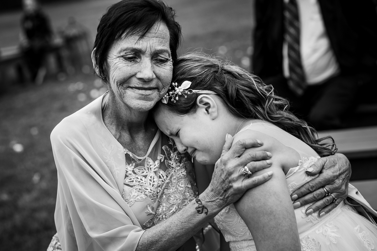 emotional photo of bride's mom holding groom's daughter as she cries during ceremony