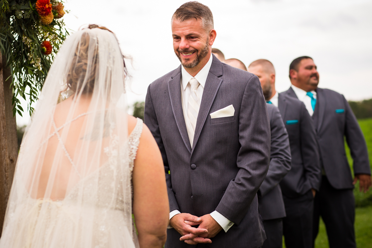 groom smiling with tears in eyes looking at bride during ceremony 