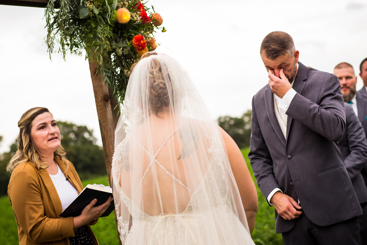 groom wiping eyes as officiant reads ceremony 