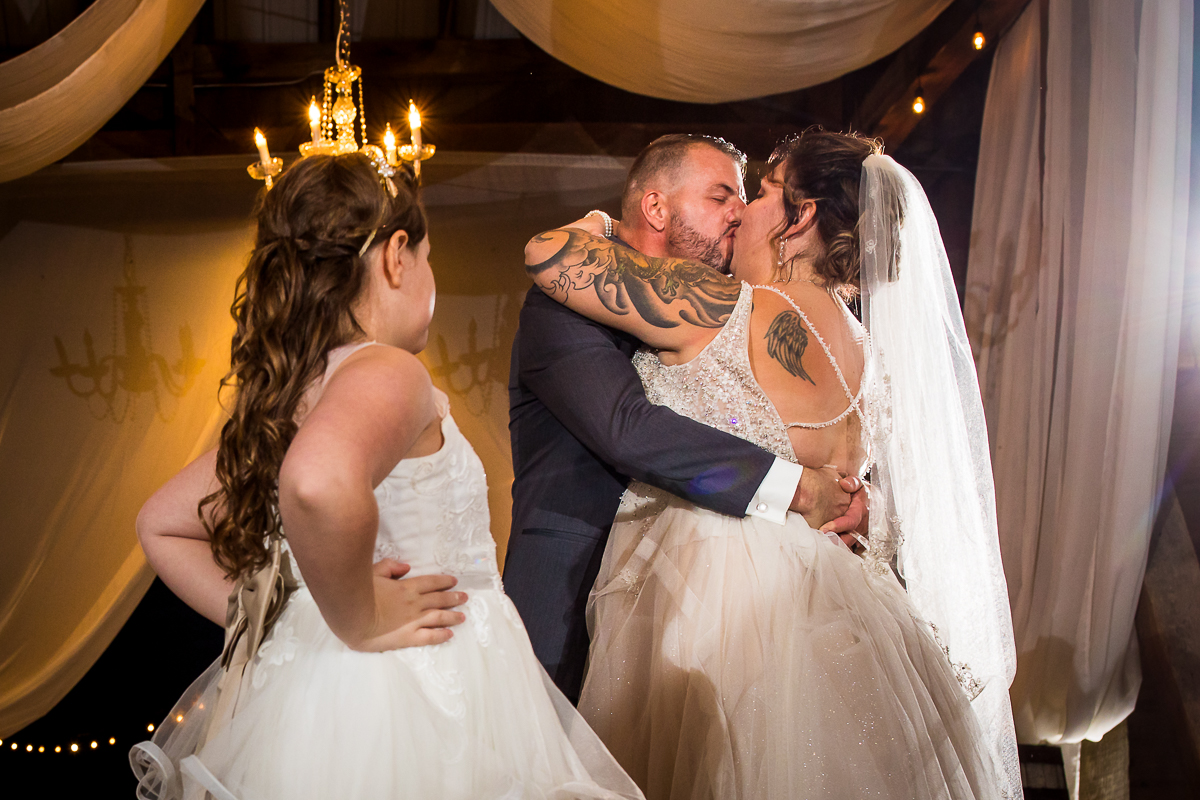 bride and groom kissing during first dance daughter steps in to interrupt 